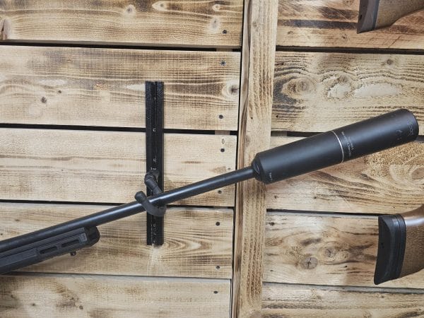 Black air gun with a silencer mounted on a wooden wall display.