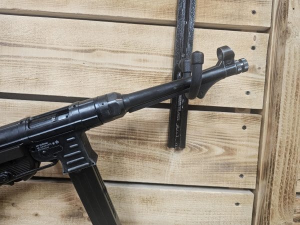 Close-up of a black air gun mounted on a wooden wall with a textured finish.