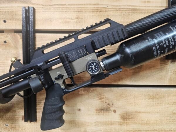 M3 air gun featuring a pressure gauge and carbon fiber tank mounted on a wooden wall.