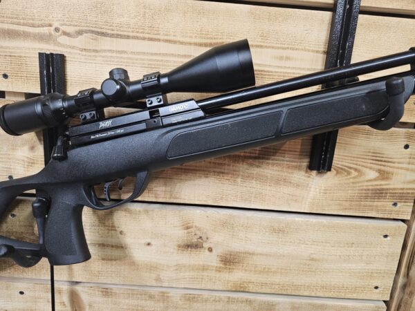 Black air gun with a mounted scope resting against a wooden surface.