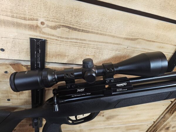 Gamo air rifle featuring a mounted scope, displayed against a wooden backdrop.